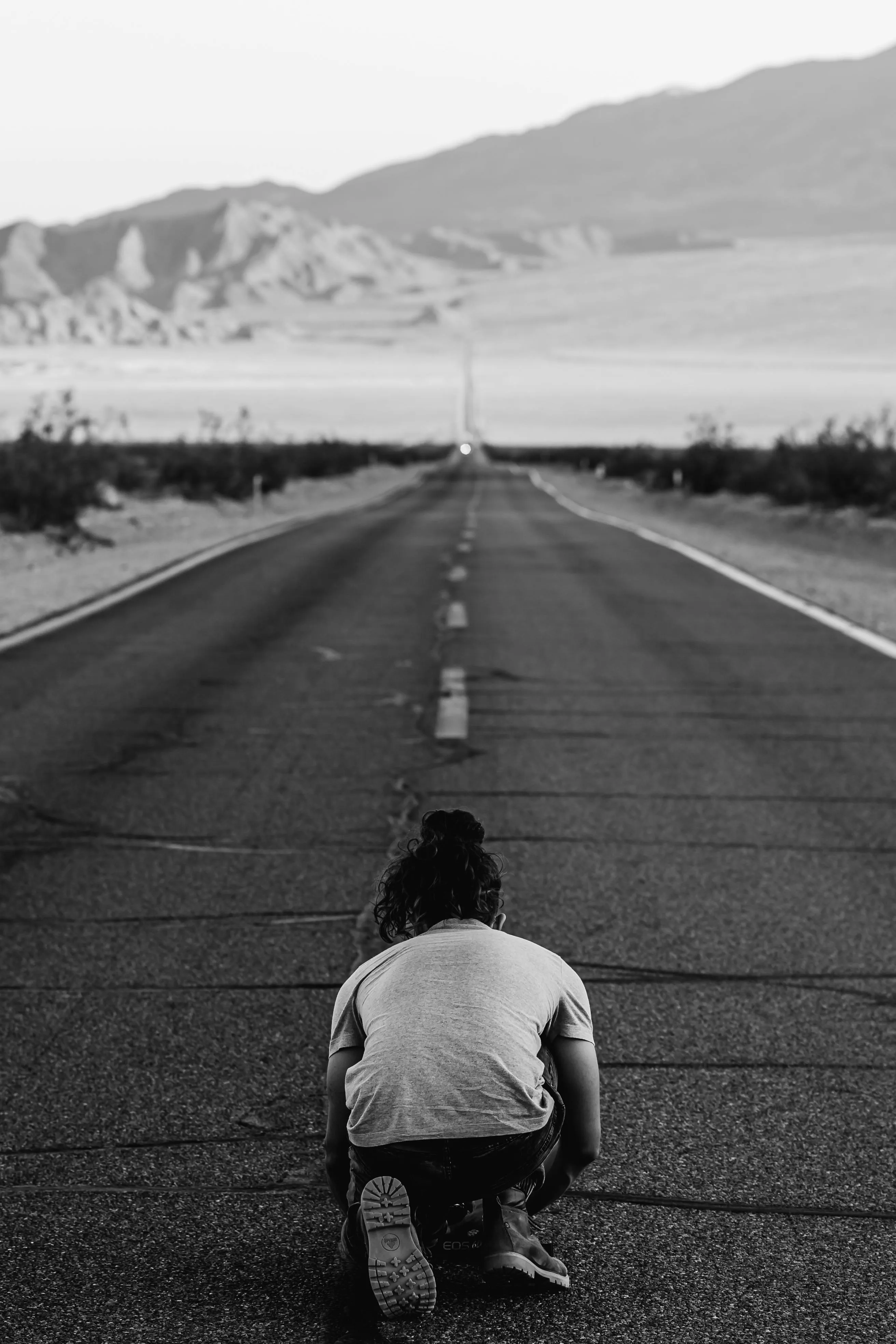 Person sitting alone on an endless road, facing the weight of a hard lesson